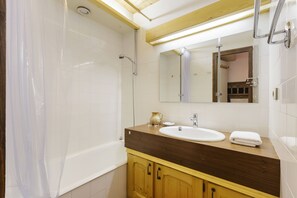 Uma casa de banho moderna com banheira, lavatório e espelho.