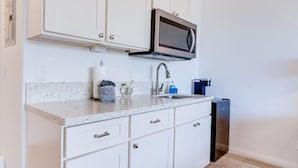 A modern kitchen with white cabinets, a stainless steel microwave, a sink, and a dishwasher. - Unit 18 Waena Inn - Maui Private Suite (Wailuku)