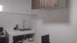 Una cocina con baldosas blancas, un lavamanos de acero inoxidable y armarios de madera.