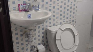 Un baño con lavamanos blanco, inodoro y azulejos de pared con diseño.