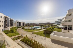 A modern residential complex with a central swimming pool, surrounded by greenery and pathways.