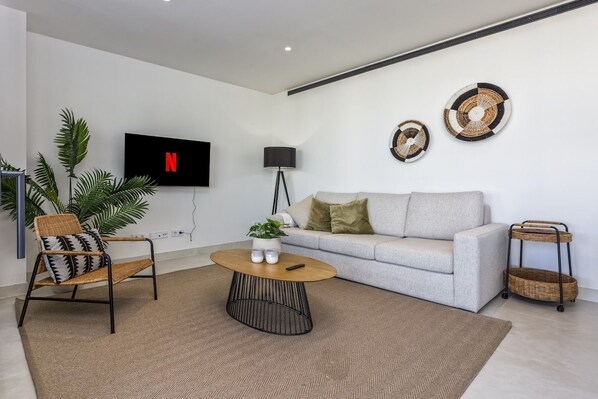 A modern living room with a sofa, a coffee table, a TV, and decorative wall art.