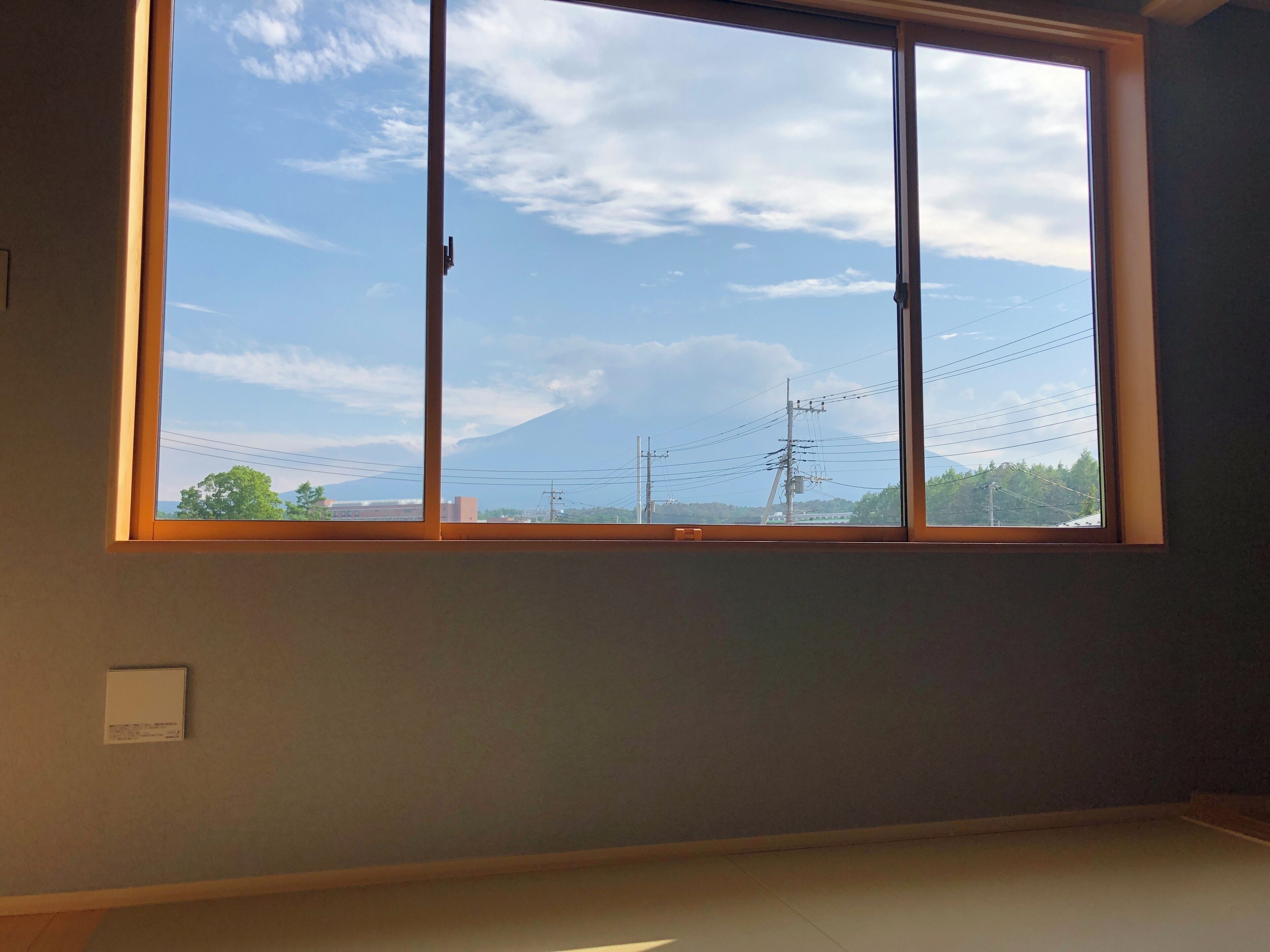 A room with a large window overlooking a mountain and power lines.