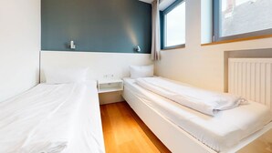 Une chambre avec deux lits, une table de chevet et une fenêtre.
