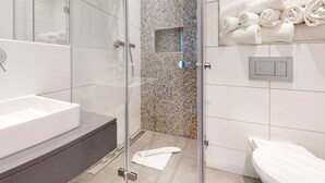Une salle de bain moderne avec une douche à parois de verre, une grande baignoire et un lavabo blanc.