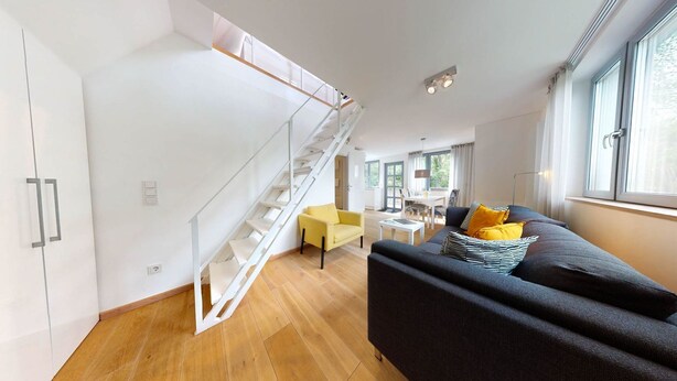 A modern interior with a staircase, a sofa, and a dining area.