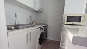 A compact kitchen with a washing machine, a microwave, and a sink.