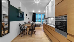 A modern kitchen with a built-in oven, a dining area with a table and chairs, and a view of the outside through large windows. - Central & Modern Apartment Reykjavik with balcony 204 (Reykjavík)