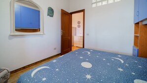 Un dormitori amb un llit, un armari, un mirall i una porta que dona a una altra habitació.