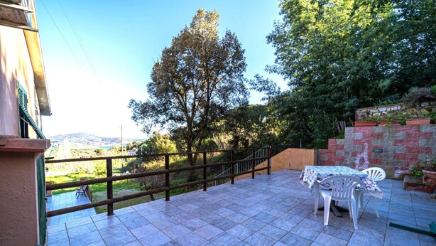 A patio with a table and chairs, a stone wall, and a view of the countryside.