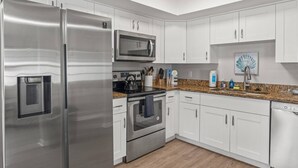 Una cocina moderna con electrodomésticos de acero inoxidable, armarios blancos y encimera de granito.