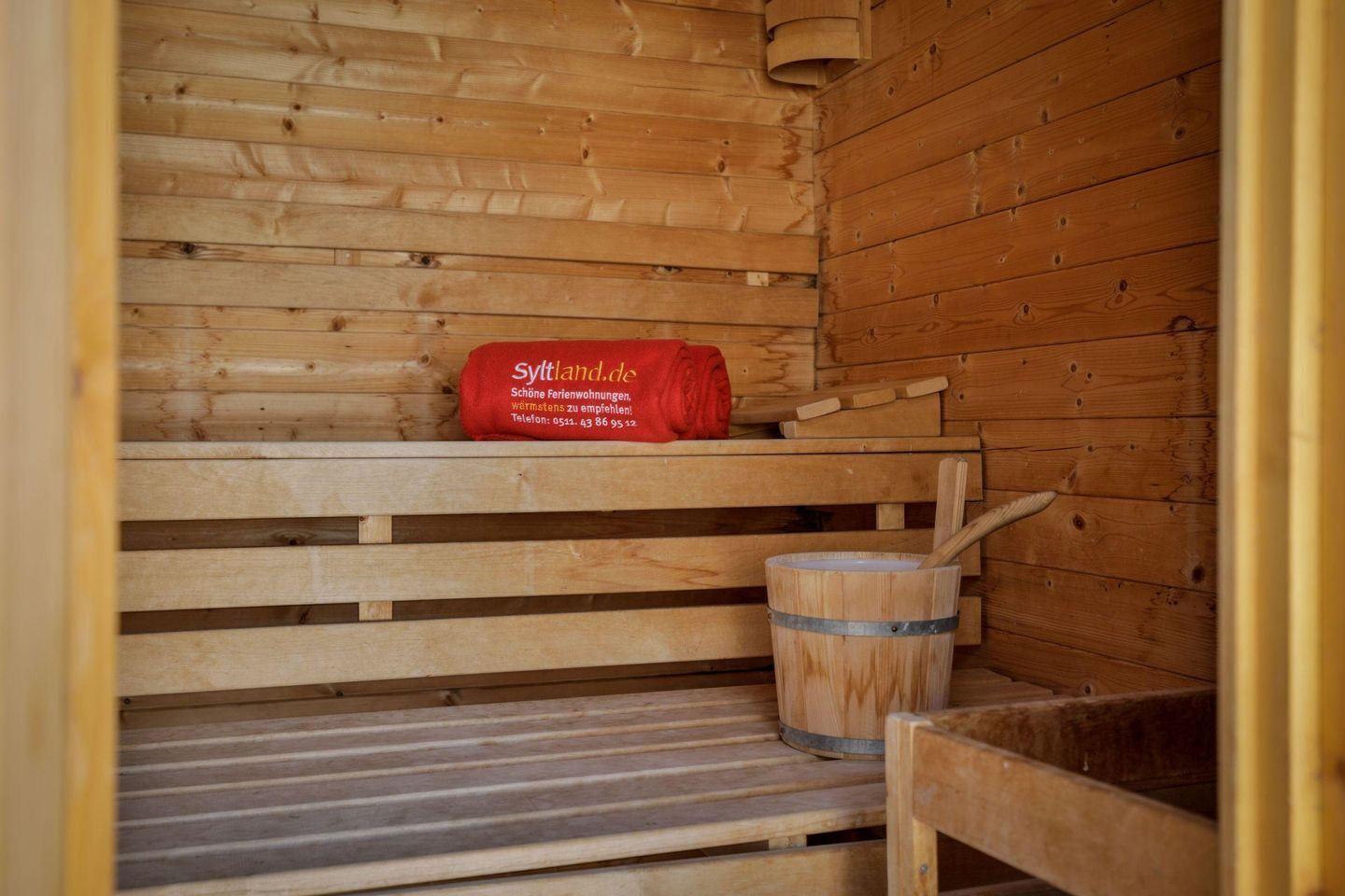 Una sauna amb seients de fusta i una tovallola vermella.