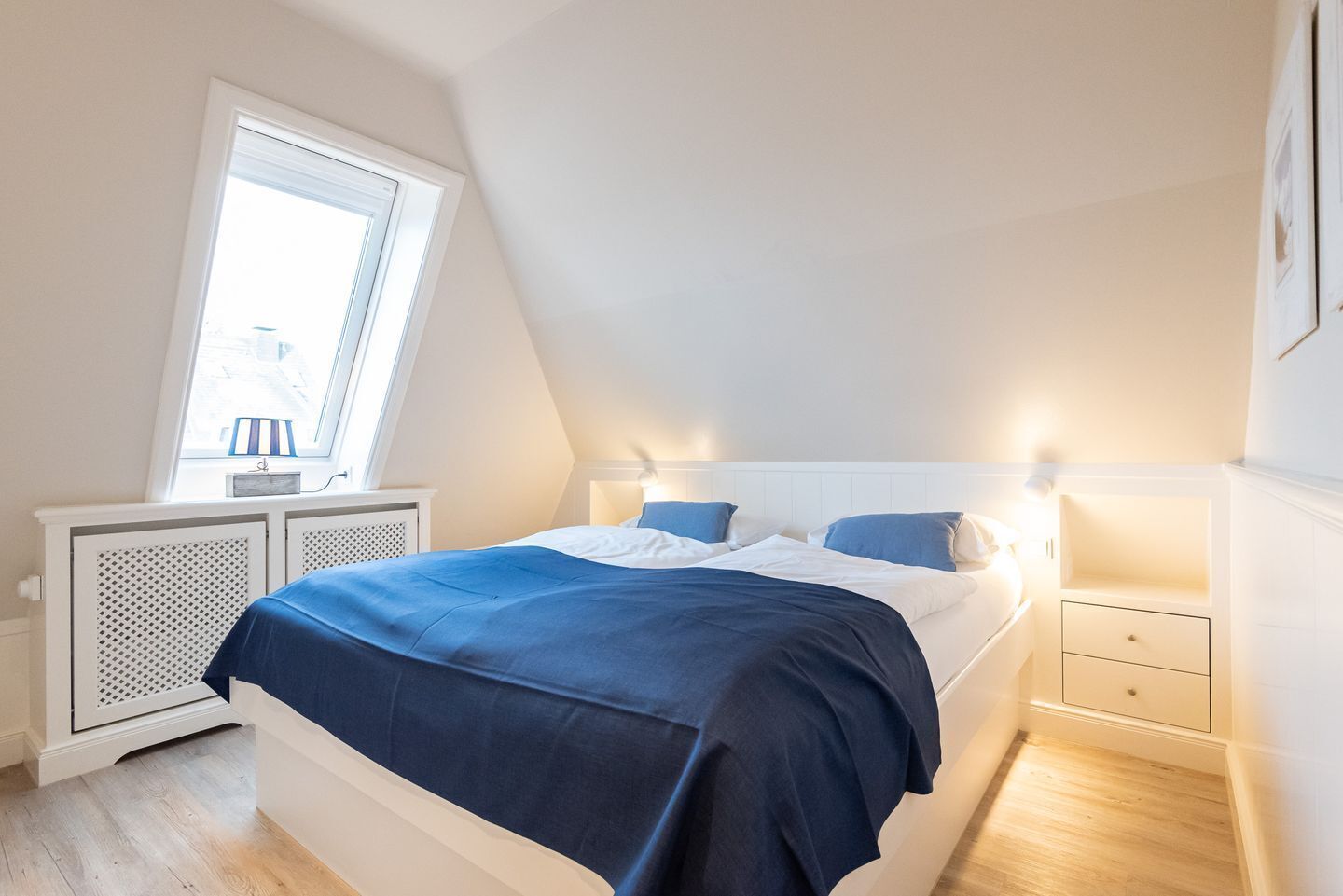 A bedroom with a bed, bedside tables, a window, and a radiator.