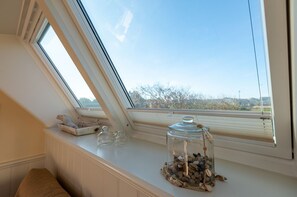 Una habitación con tragaluz, un tarro de cristal con guijarros y una pequeña escultura en el alféizar de la ventana.