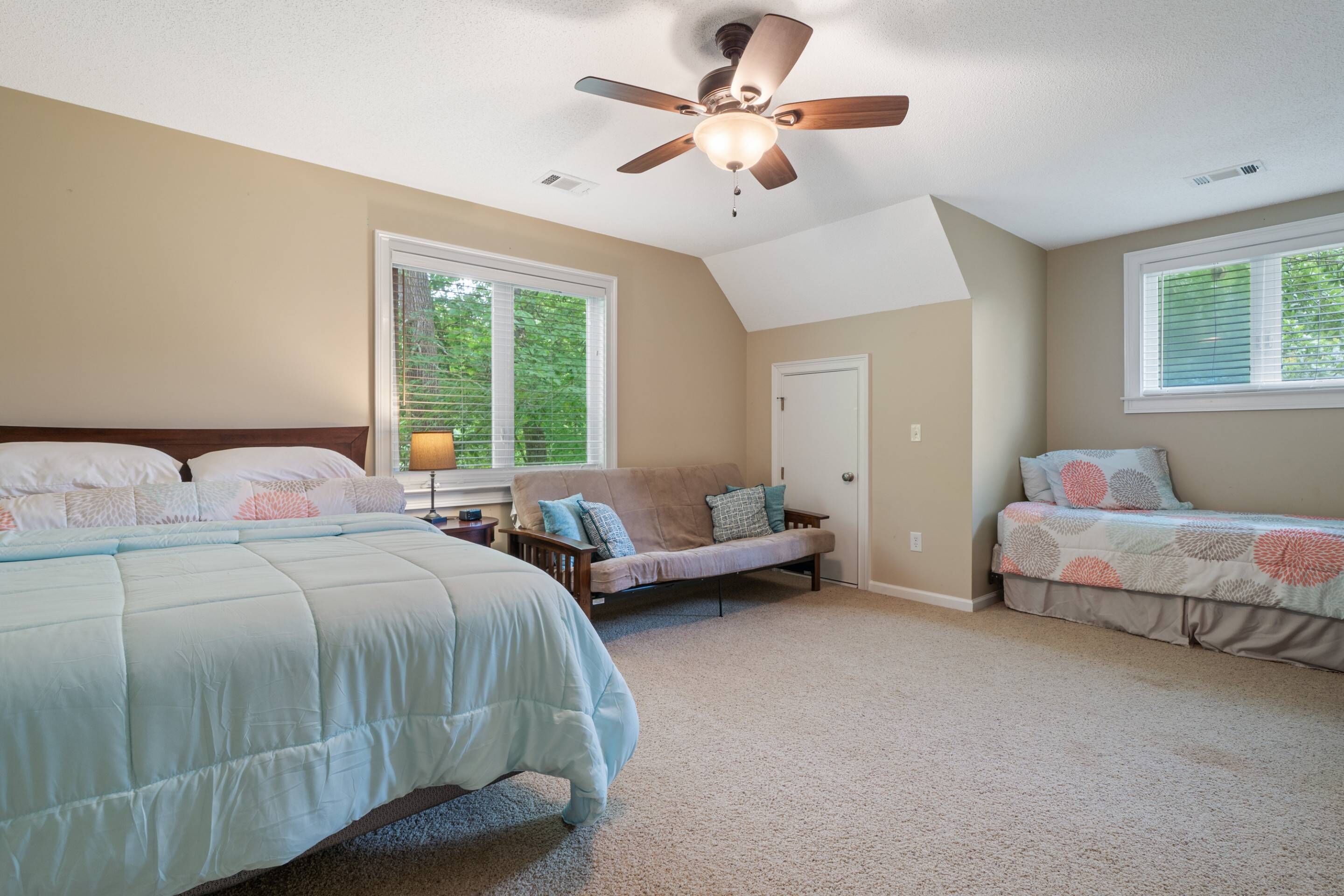 A bedroom with a large bed, a sofa, and a desk.