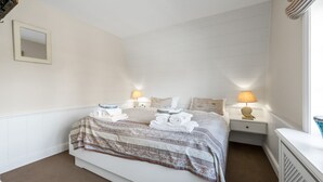 Habitación de hotel con cama, dos mesitas de noche, un espejo y una ventana con cortinas.