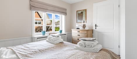 A bedroom with a bed, a dresser, a window with curtains, and a door.
