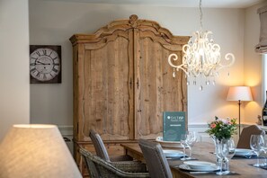 A dining area with a wooden cabinet, a chandelier, and a table set for two.