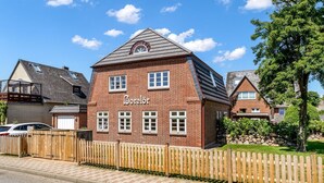 Ein Backsteinhaus mit der Aufschrift 'Borelor', einem Holzzaun und einem gepflasterten Weg.