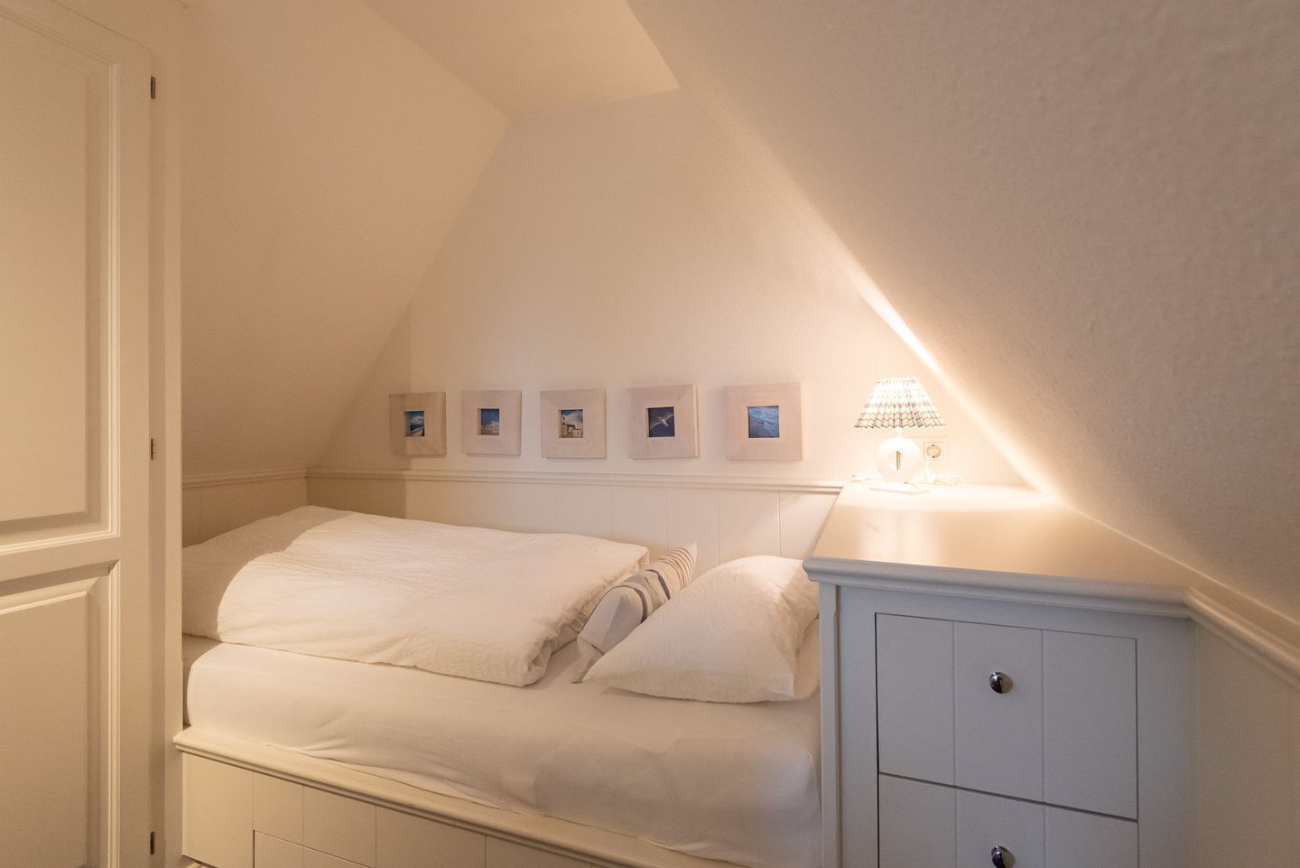 Un dormitorio con cama, mesita de noche y lámpara de pared.