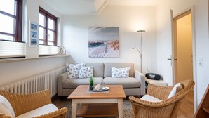 A cozy living room with a sofa, two wicker chairs, a coffee table, and a floor lamp.
