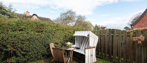 A patio with a table and chairs, surrounded by a wooden fence and dense greenery.