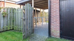 A covered outdoor area with a wooden fence, a metal gate, and a brick wall.