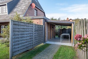 A house with a covered patio, a brick exterior, and a wooden fence.