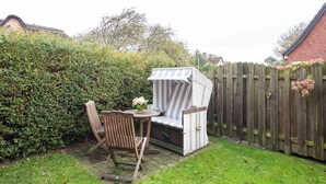 A patio area with a wooden chair, a small round table, and a striped outdoor sofa.