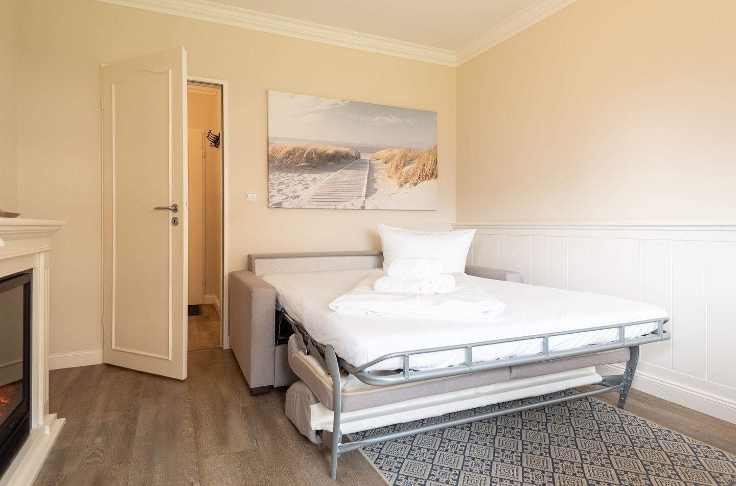 A bedroom with a metal bed frame, a white mattress, and a patterned rug.