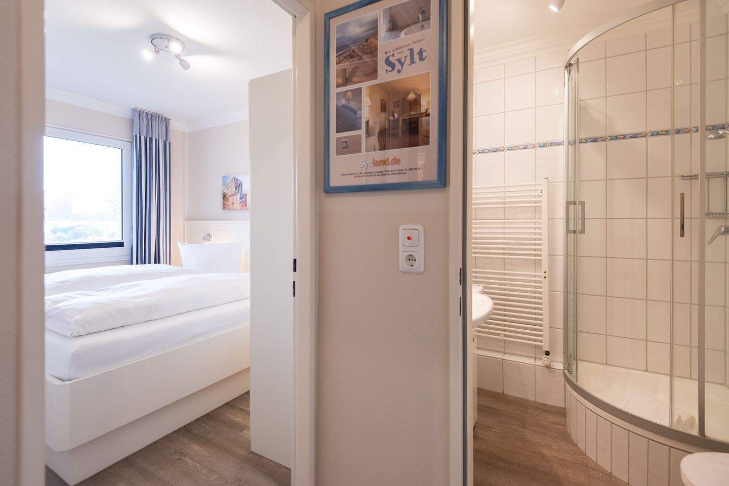 A hotel room with a bed, a shower, and a poster on the wall.