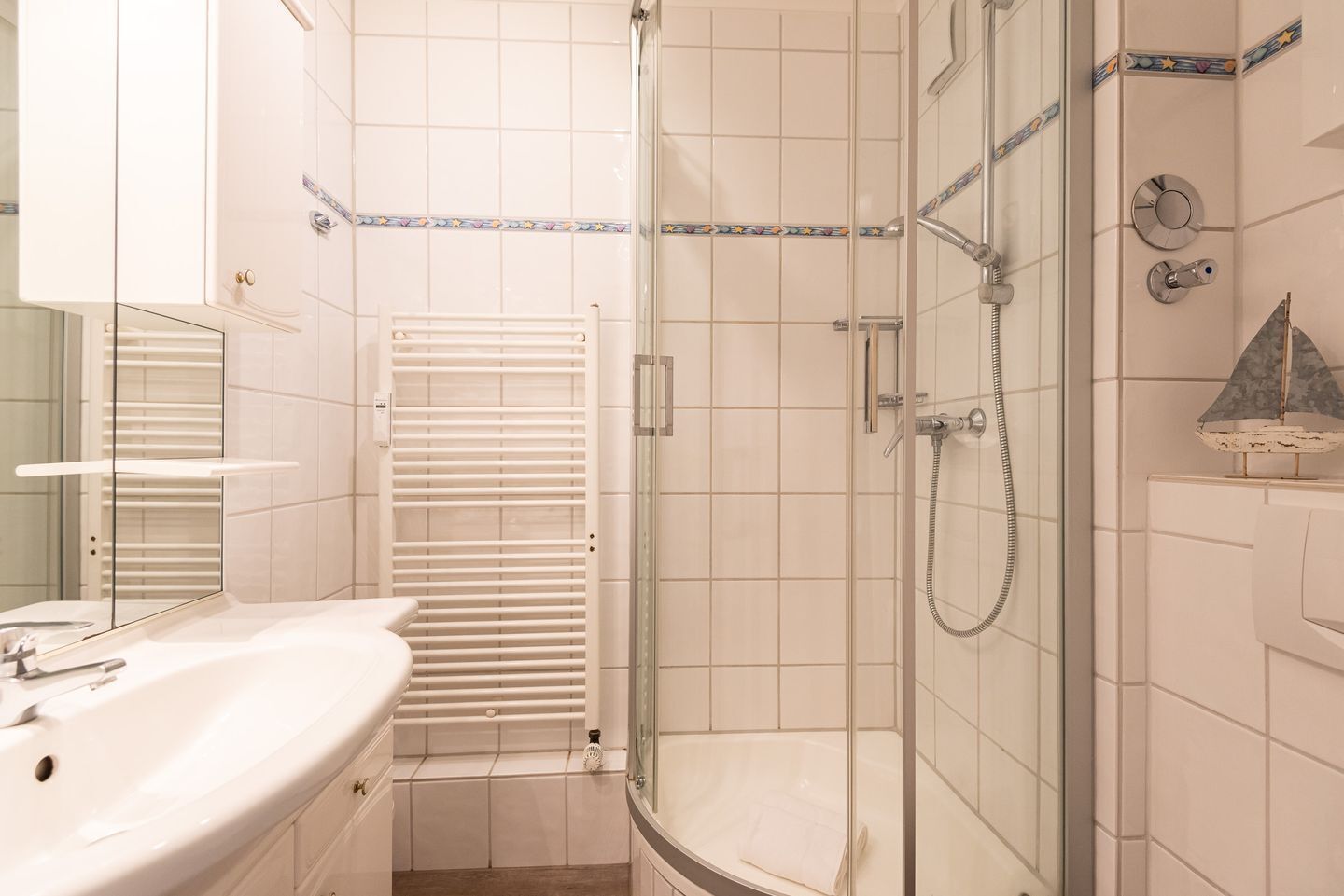 A modern bathroom with a glass-enclosed shower, a white sink, and a mirror.