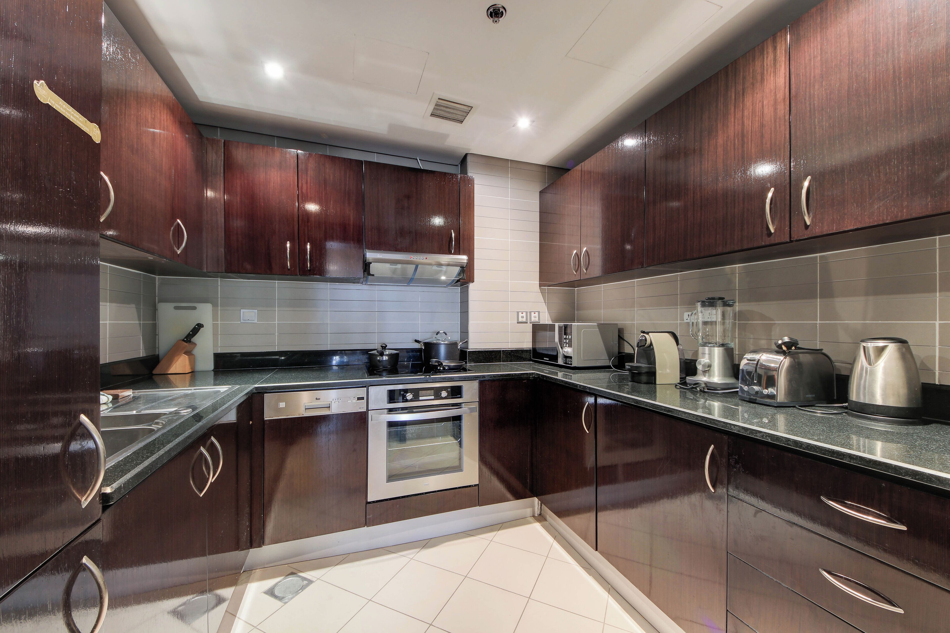 A modern kitchen with dark wooden cabinets, stainless steel appliances, and a tiled backsplash.