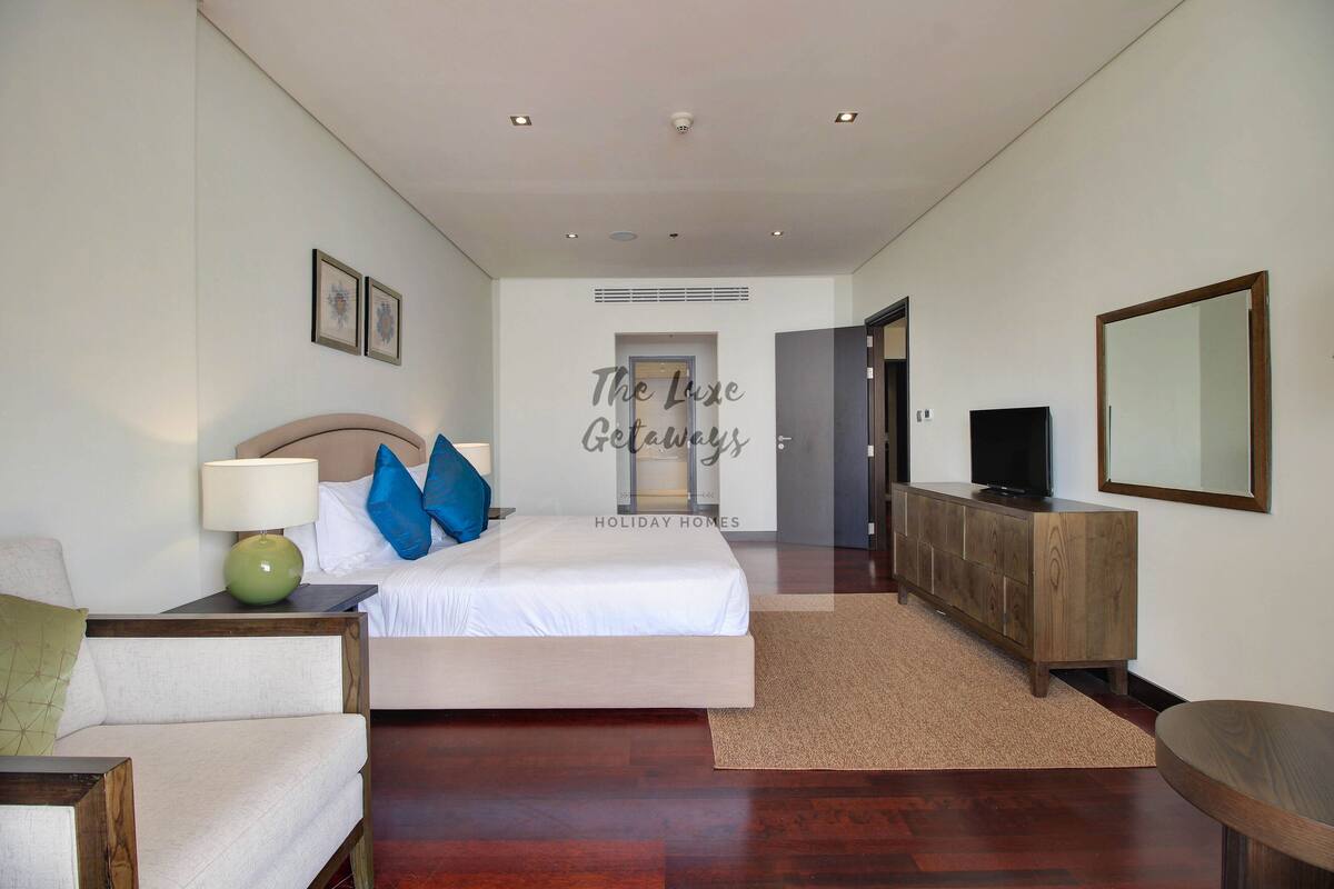A hotel room with a bed, a TV, a wooden dresser, and a mirror.
