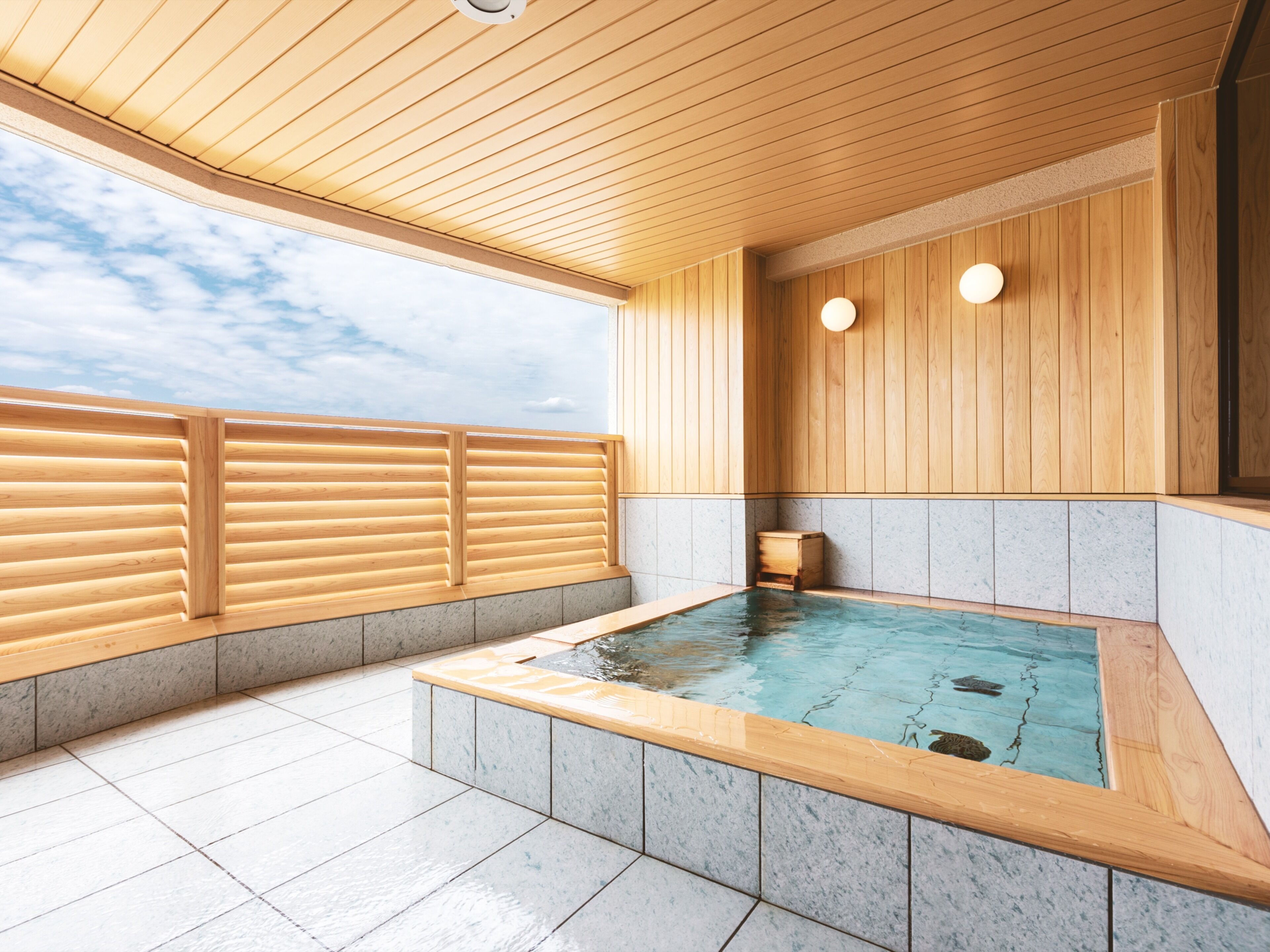 A spa area with a wooden deck, a hot tub, and a view of the sky.