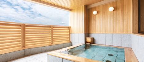 A spa area with a wooden deck, a hot tub, and a view of the sky.