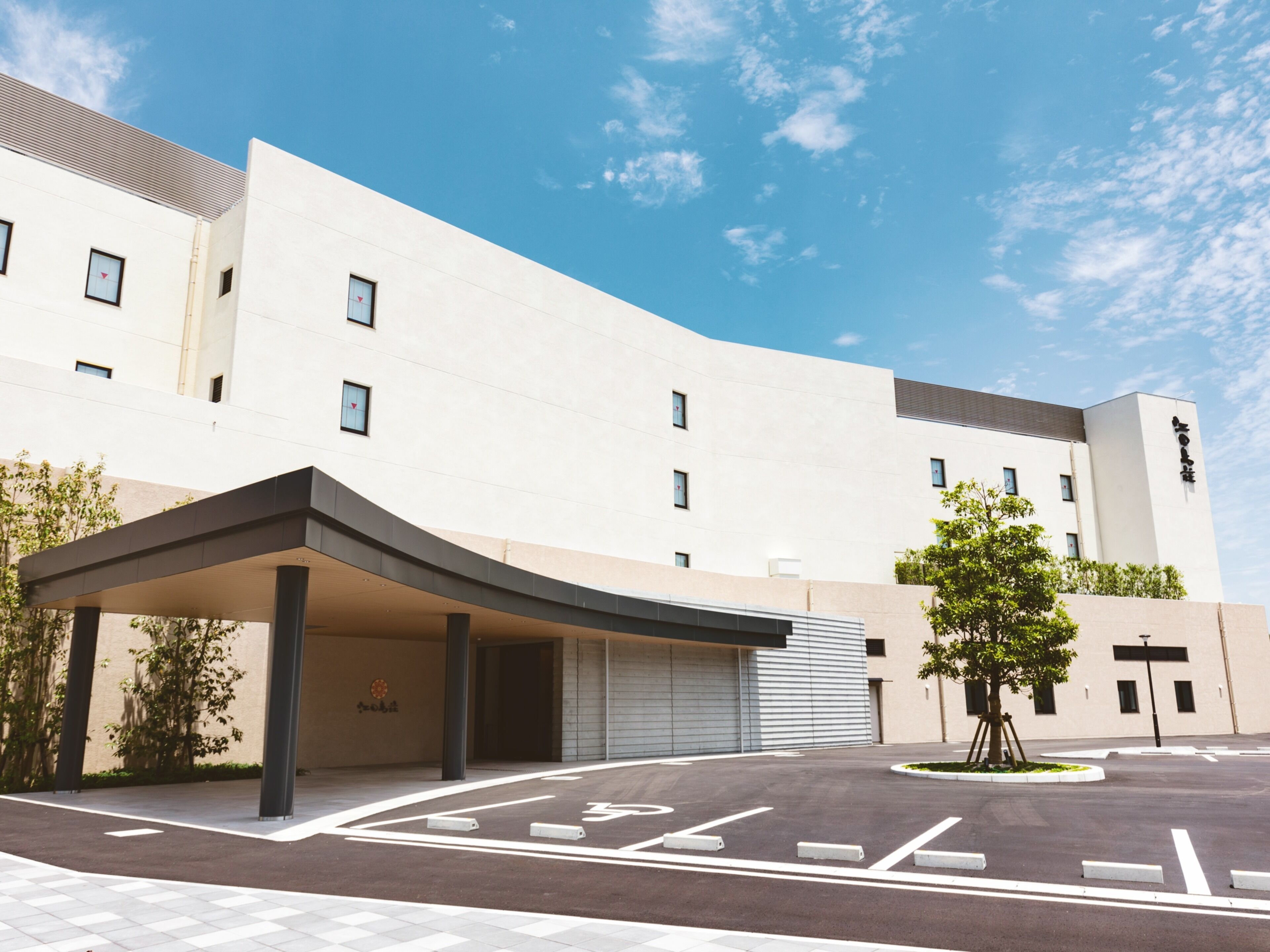 A modern building with a curved entrance, a covered waiting area, and a clear sky.