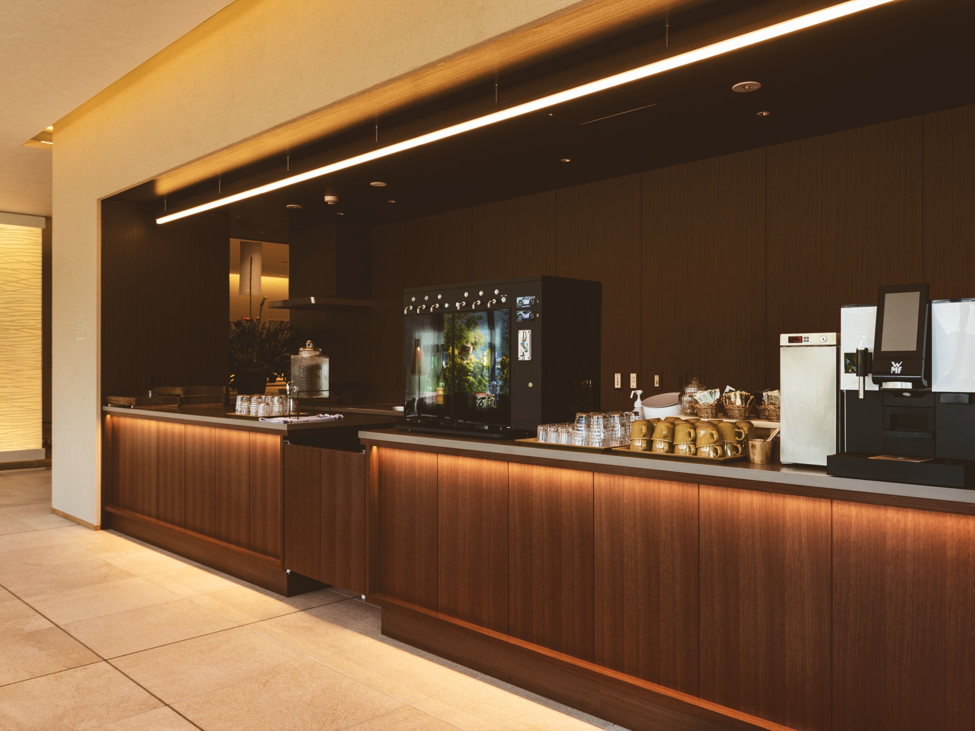 A modern kitchen area with a built-in coffee machine, a refrigerator, and a microwave.