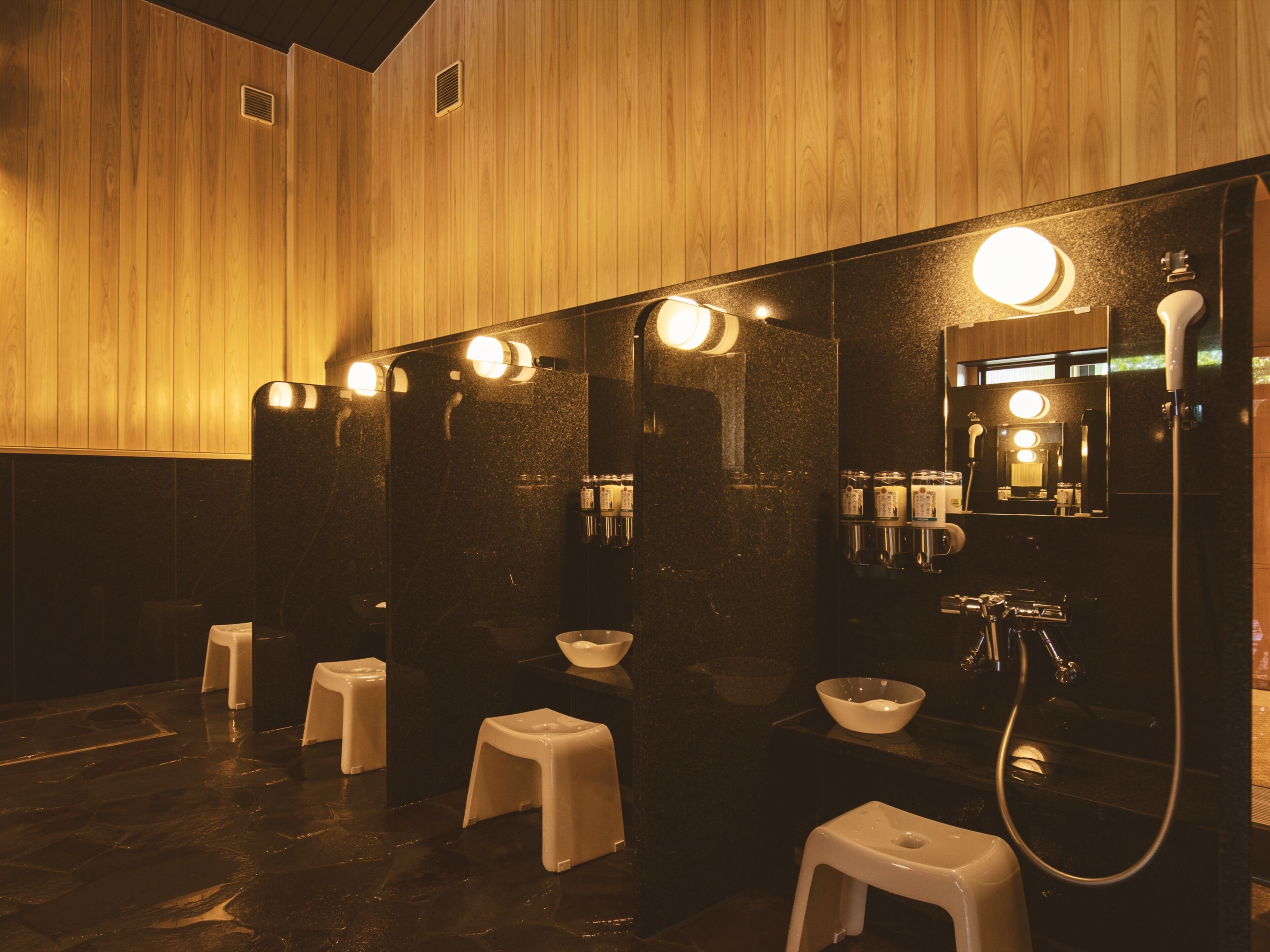 Une salle de bain moderne avec un lambris en bois, plusieurs vasques et un grand miroir.