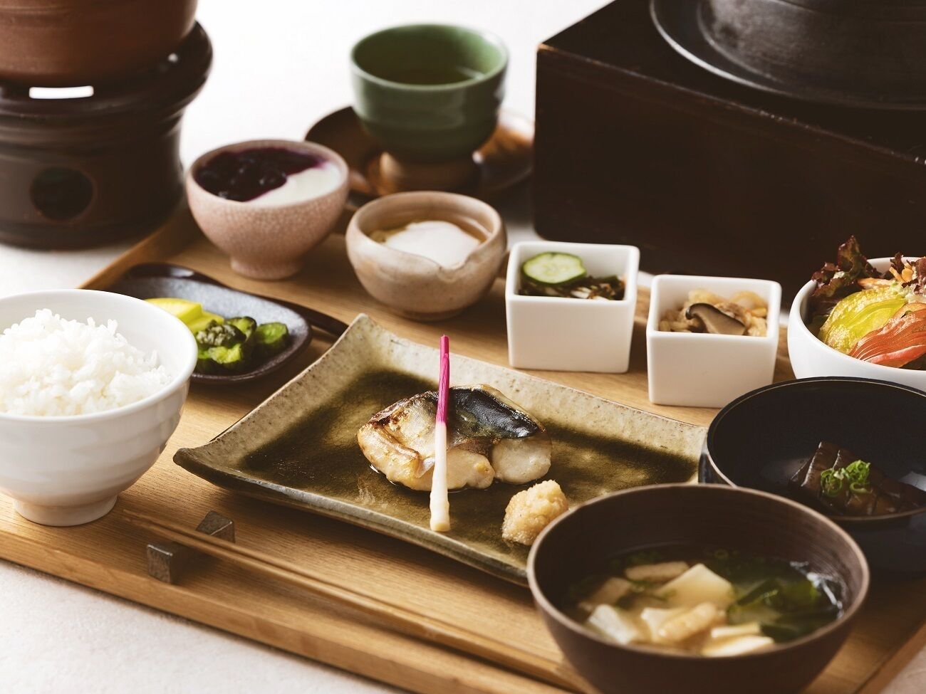 Una comida tradicional japonesa con diversos platos, incluyendo arroz, pescado y sopa.
