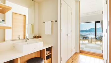 A modern bathroom with a large mirror, a sink, and a wooden chair.