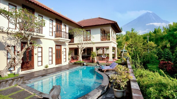 Un bâtiment à deux étages doté d’une piscine, de mobilier d’extérieur et offrant une vue sur une montagne.