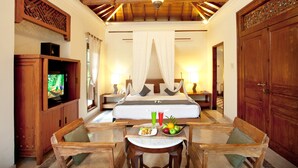 Une chambre d’hôtel avec un grand lit, une télévision, une table à manger avec des chaises et un buffet en bois.
