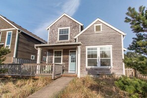 A two-story house with a front porch, a small deck, and a number '6' on the front door.