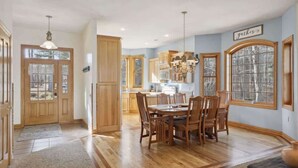A spacious kitchen with wooden cabinets, a dining table with chairs, and a large window providing natural light.