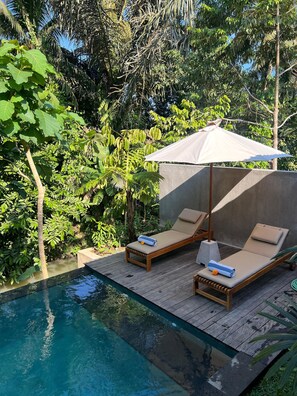 A poolside area with two lounge chairs and a canopy umbrella. - RUMAH KAYU RESORT (Ubud)