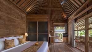 A wooden room with a bed, a desk, and a TV. - RUMAH KAYU RESORT (Ubud)