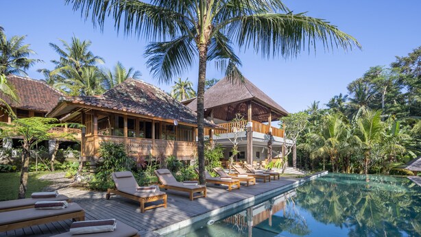 A resort with a pool, lounge chairs, and tropical vegetation. - RUMAH KAYU RESORT (Ubud)
