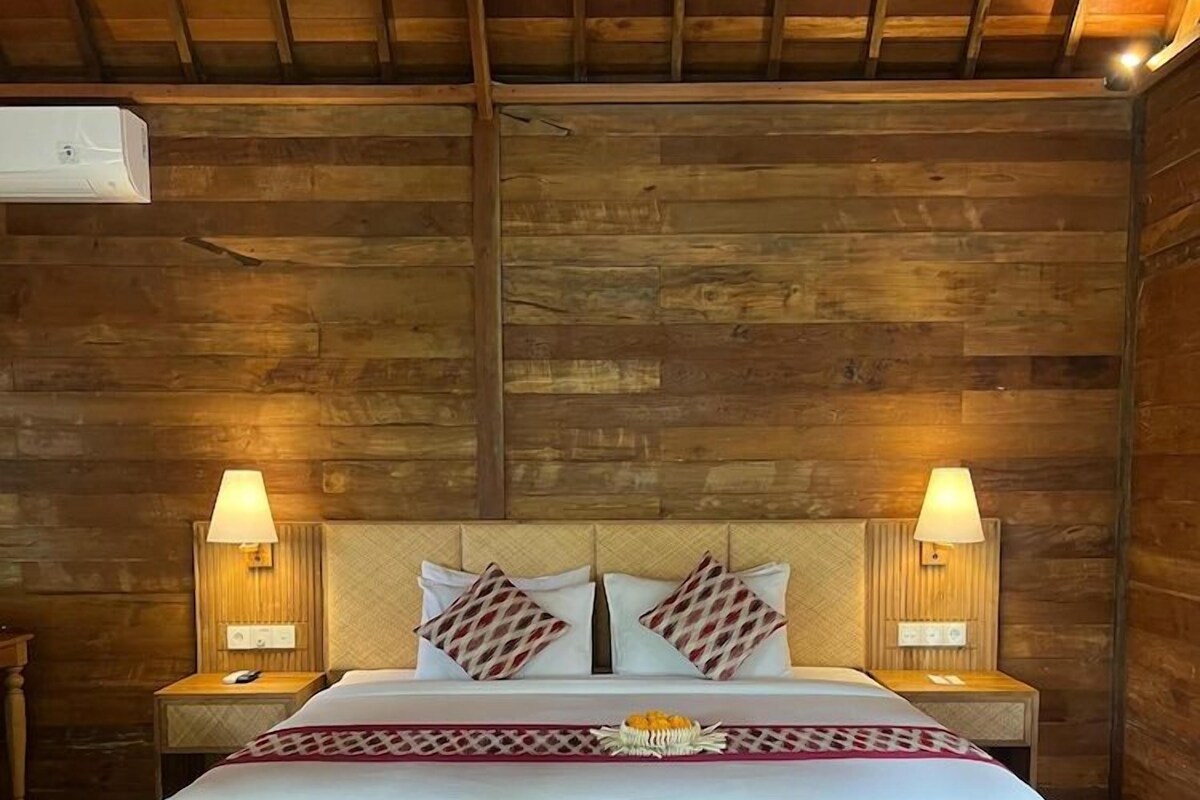 A wooden-framed bed with a headboard, two bedside lamps, and a decorative pillow arrangement.