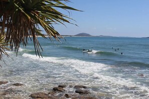 A beach with clear water, waves, and surfers. - Mooloolaba Beach House- Pet friendly  (Mooloolaba)